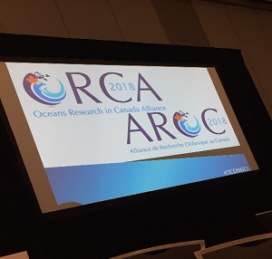 Écran de projection montrant le logo 2018 de l’AROC en français et en anglais. 