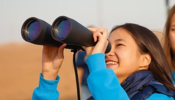 A girl looking into the sky with a pair of binoculars