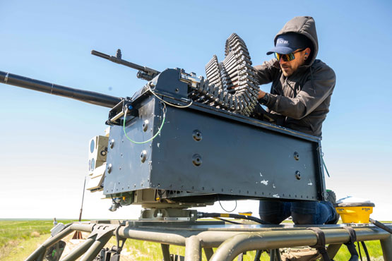A person loads ammunition into a weapon mounted on a vehicle.