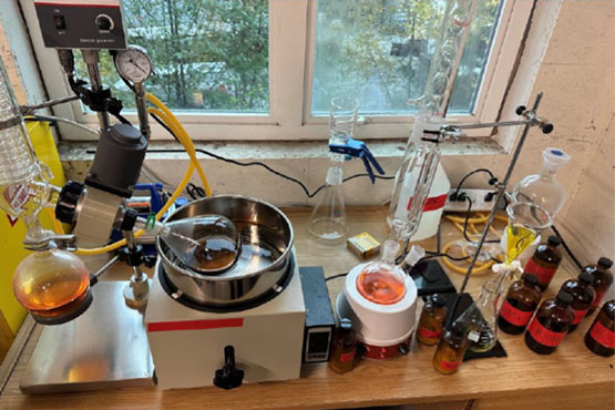 A table with chemistry equipment, a few glass containers, and a container with liquid in it.