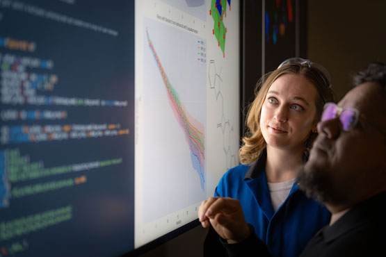 Two people looking at a screen with code