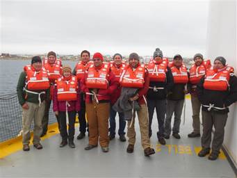 Most of the science crew after the safety drill on the deck of Wilfrid Laurier with Cambridge Bay in the background.