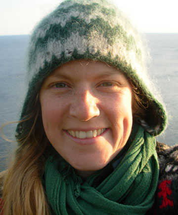 Une chercheur scientifique portant une tuque et une écharpe sourit à la caméra.
