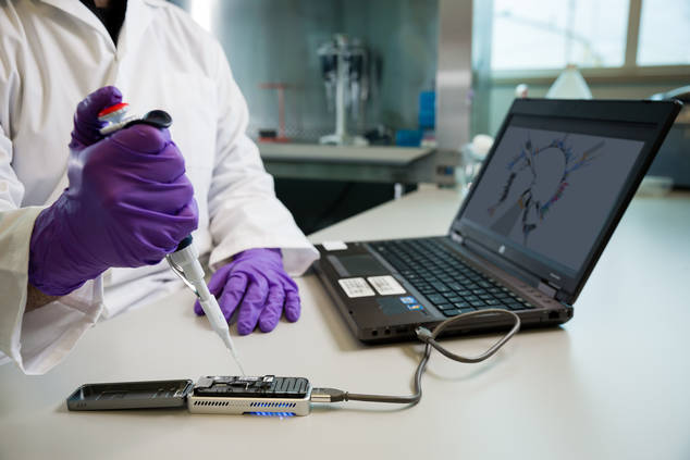 La recherche sur le génome révolutionne nos laboratoires; on voit ici un scientifique déposer un échantillon dans un séquenceur portatif.