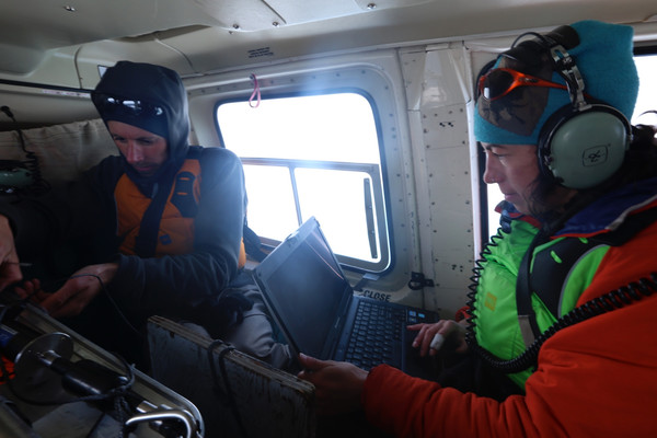 When you are doing fieldwork, your office can be anywhere! Here, we are programming instruments as we catch a ride in a helicopter to our next sampling site on the Milne Ice Shelf.
